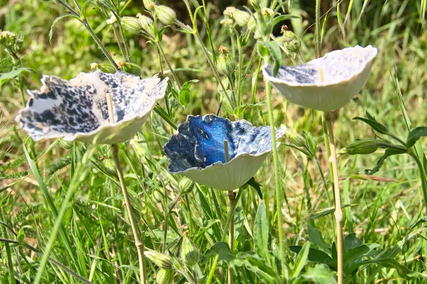 Trois fleurs en porcelaine, pièces décoratives au milieu des herbes du jardin